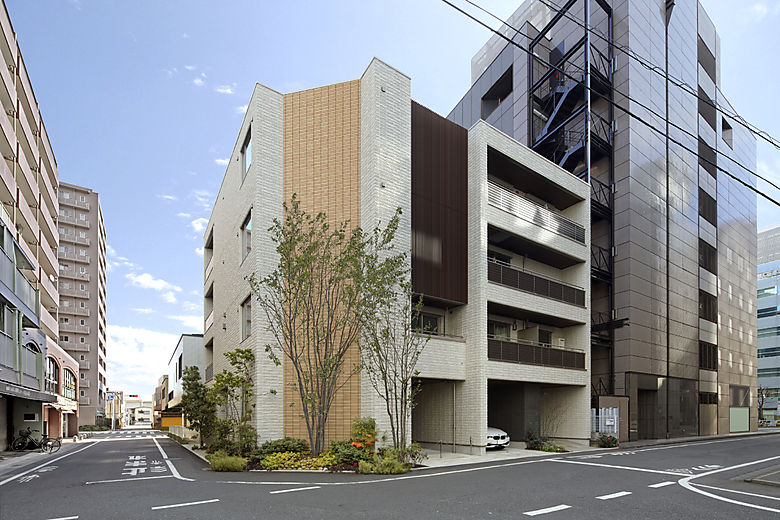 角地に建つスタイリッシュな４階建て。３，４階の２世帯居住ゾーンにはルーバーを貼り、アクセントに。